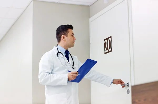 Doctor with clipboard opening hospital ward door — Stock Photo, Image