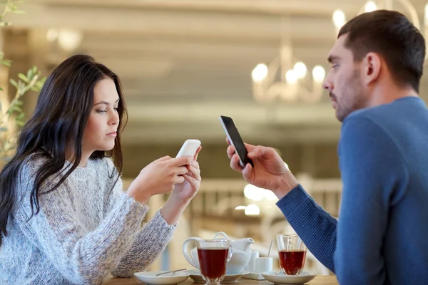 Pareja con teléfonos inteligentes beber té en la cafetería —  Fotos de Stock