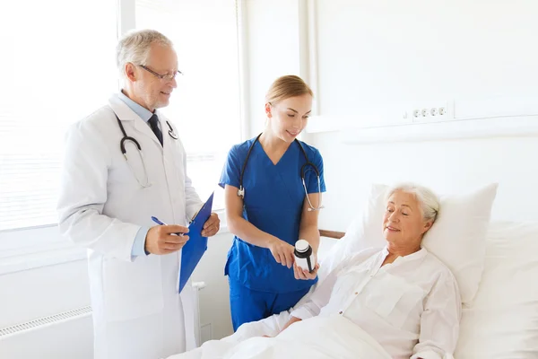 Doctor giving medicine to senior woman at hospital — Stock Photo, Image