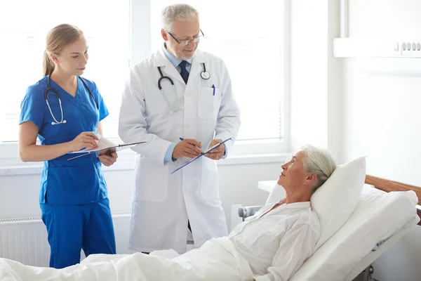 Médico e enfermeira visitando mulher idosa no hospital — Fotografia de Stock