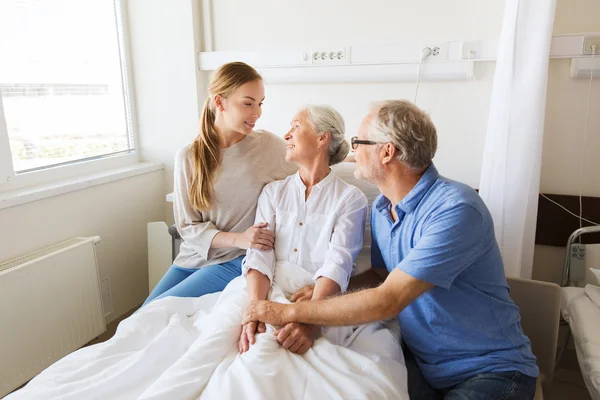 Familia feliz visitando a la mujer mayor en el hospital — Foto de Stock