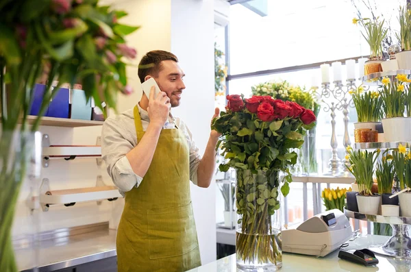 Hombre con smartphone y rosas rojas en floristería — Foto de Stock