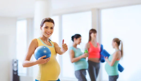 Mujer embarazada con pelota en el gimnasio mostrando los pulgares hacia arriba — Foto de Stock