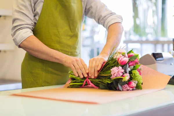 Florista embrulhando flores em papel na loja de flores — Fotografia de Stock