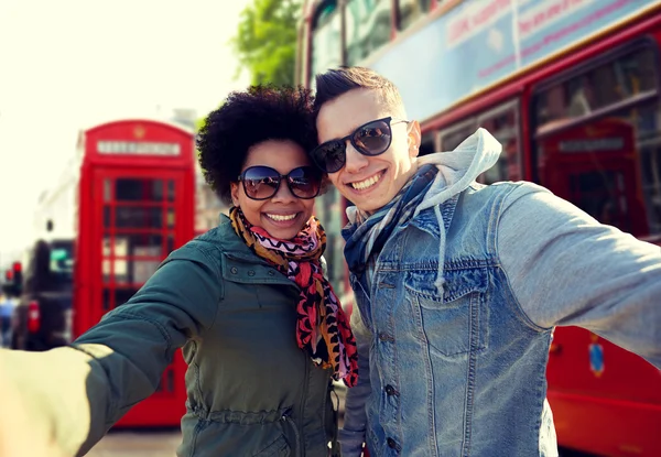 Happy teenage couple taking selfie in london city — Stock Photo, Image