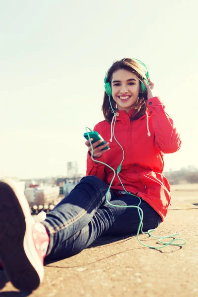 Šťastná mladá žena s smartphone a sluchátka — Stock fotografie