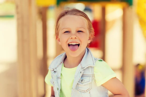 놀이터에 혀를 보여주는 행복 한 어린 소녀 — 스톡 사진