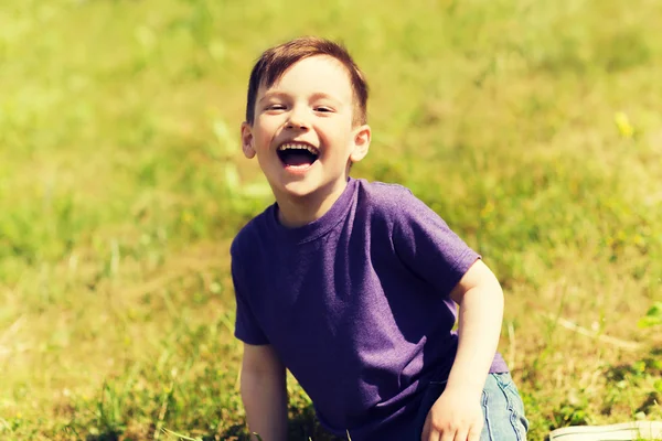 Heureux petit garçon assis sur l'herbe à l'extérieur — Photo