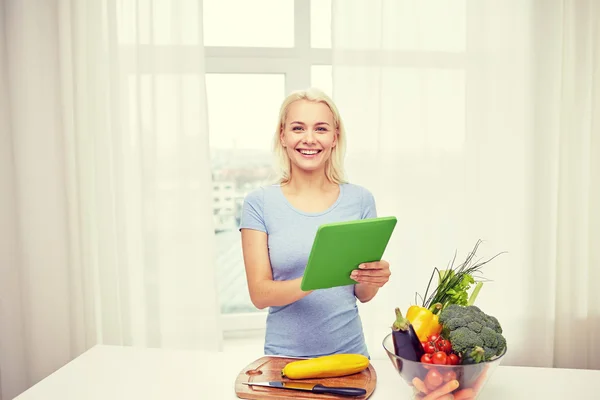Smiling young woman with tablet pc cooking at home — Stock Photo, Image