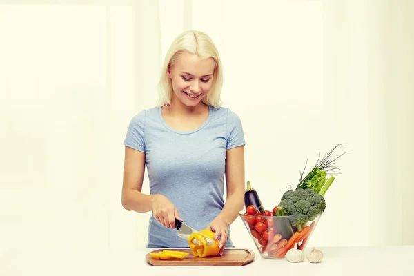 Sonriente joven mujer picando verduras en casa — Foto de Stock