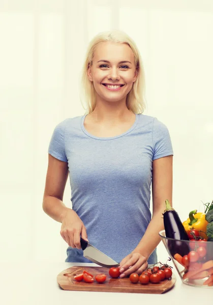 Lächelnde junge Frau, die zu Hause Gemüse hackt — Stockfoto