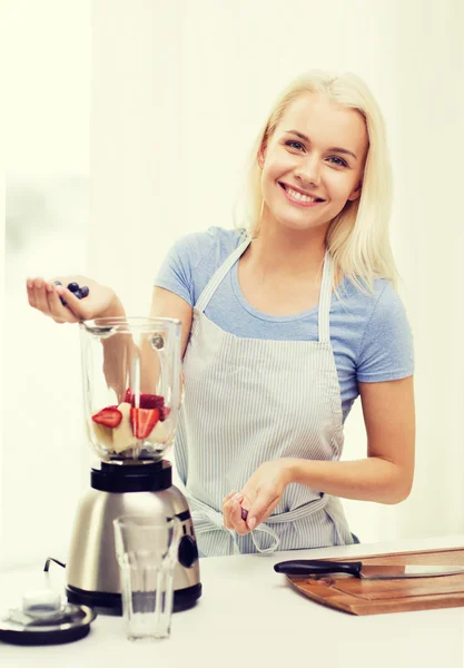 Mulher sorridente com liquidificador preparando shake em casa — Fotografia de Stock