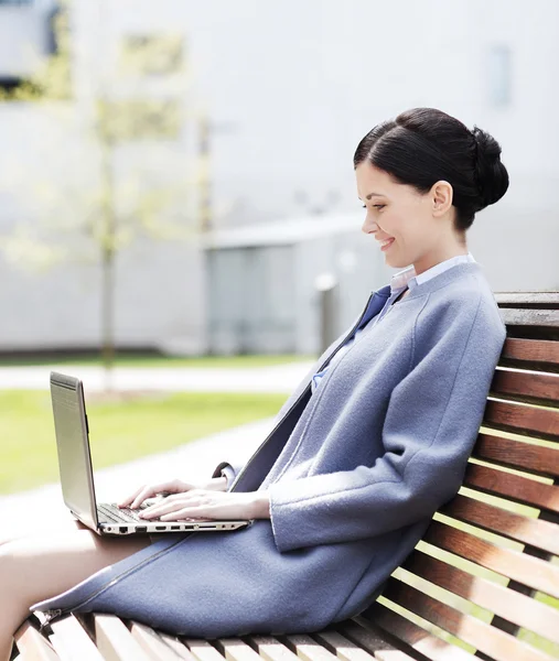 Smiling business woman with laptop in city — Stock Photo, Image