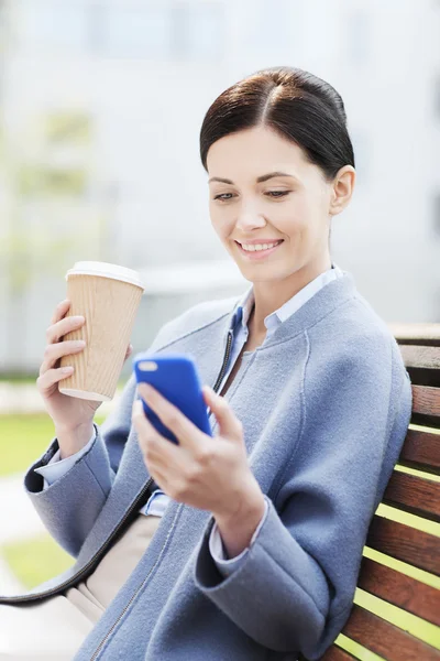 Smiling woman with coffee and smartphone — Stock Photo, Image