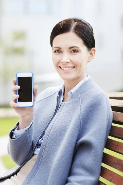 Unga leende affärskvinna visar smartphone — Stockfoto