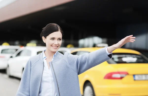 Lächelnde junge Frau winkt mit der Hand und fängt Taxi — Stockfoto