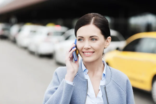 Lachende vrouw met smartphone over taxi in stad — Stockfoto