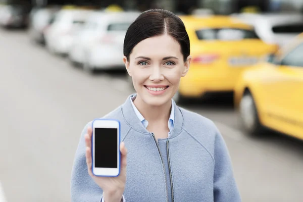 Smiling woman showing smartphone over taxi in city — Stock Photo, Image