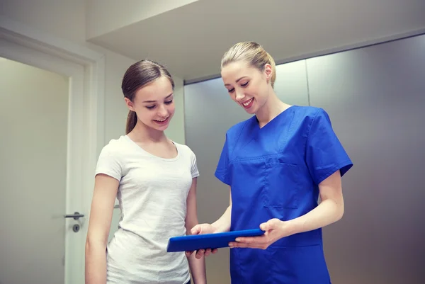 Enfermera sonriente con tableta PC y niña en el hospital — Foto de Stock