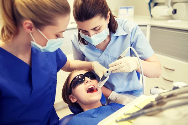 Dentistas mulheres que tratam os dentes da menina paciente — Fotografia de Stock