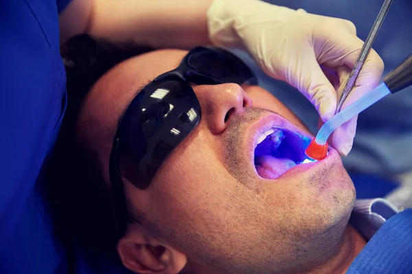 Primer plano del paciente masculino con luz de curado dental — Foto de Stock