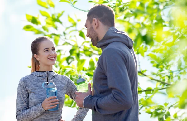 Couple souriant avec des bouteilles d'eau à l'extérieur — Photo