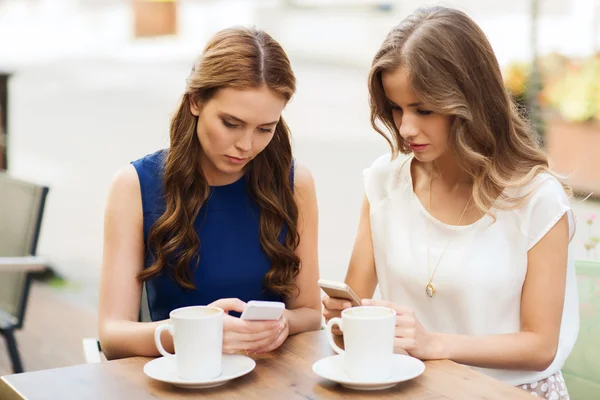 Mujeres con teléfonos inteligentes y café en la cafetería al aire libre —  Fotos de Stock