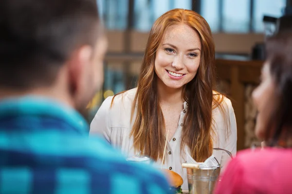 Счастливая женщина ужинает с друзьями в ресторане — стоковое фото