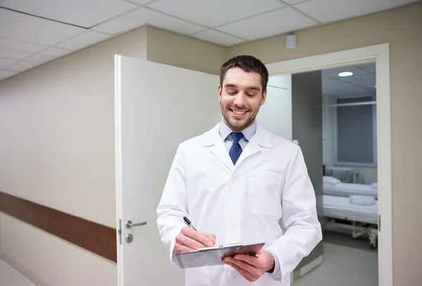 Smiling doctor with clipboard at hospital — Stock Photo, Image