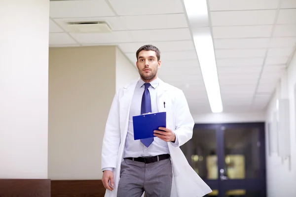 Doctor with clipboard walking along hospital — Stock Photo, Image