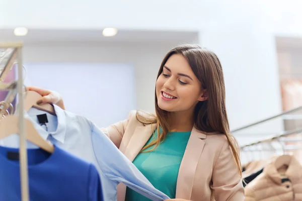 Gelukkig jonge vrouw kleding in winkelcentrum kiezen — Stockfoto