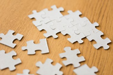 close up of puzzle pieces on wooden surface clipart