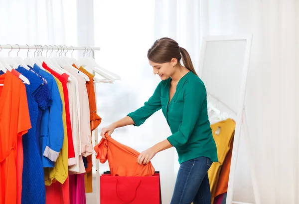 Mujer feliz con bolsas de compras y ropa en casa —  Fotos de Stock