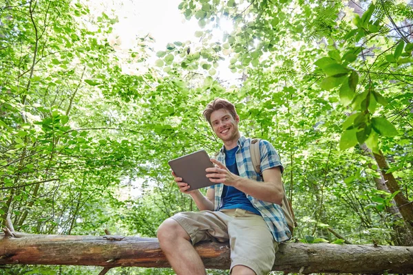 Glücklicher Mann mit Rucksack und Tablet-PC im Wald — Stockfoto
