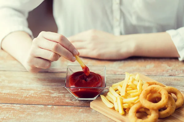Close up de mão mergulhando batatas fritas em ketchup — Fotografia de Stock