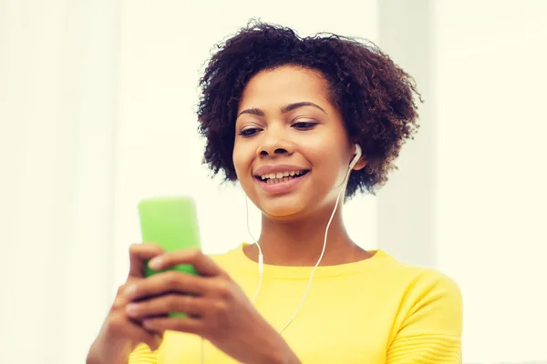 happy african woman with smartphone and earphones