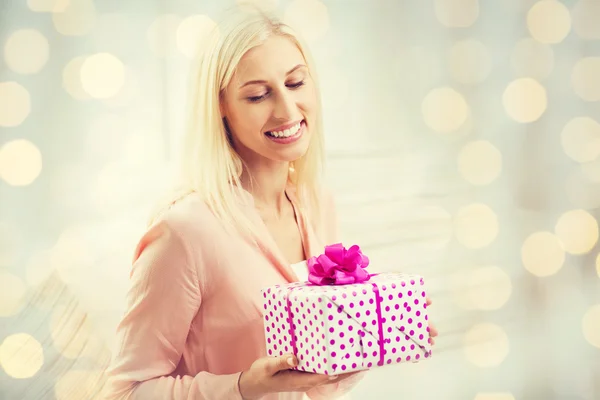 Smiling woman with gift box over holidays lights Stock Photo