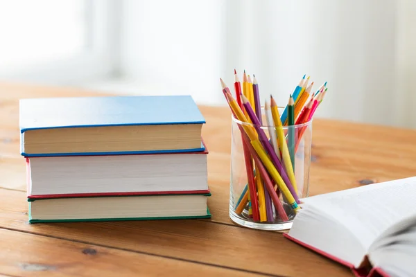 Close up of crayons or color pencils and books — Stock Photo, Image