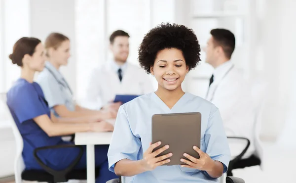 Médico feliz com tablet pc sobre a equipe na clínica — Fotografia de Stock