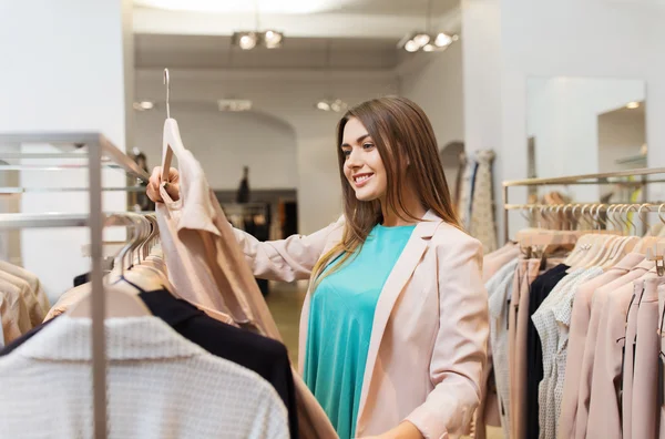 Feliz jovem mulher escolhendo roupas no shopping — Fotografia de Stock