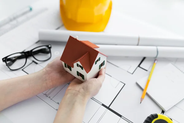 Primer plano de las manos con el modelo de la casa por encima del plano — Foto de Stock