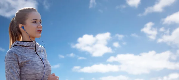 Mujer feliz con auriculares corriendo sobre el cielo azul — Foto de Stock