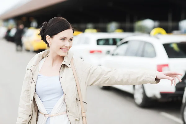 Улыбающаяся молодая женщина машет рукой и ловит такси — стоковое фото