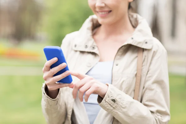 Nahaufnahme einer Frau, die im Park mit dem Smartphone telefoniert — Stockfoto