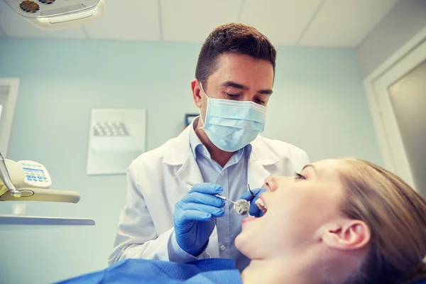 Dentista masculino en la máscara de control de dientes de paciente femenino — Foto de Stock