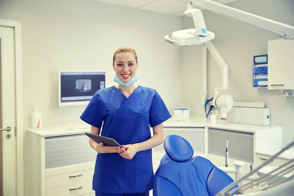 Dentista feminino feliz com tablet pc na clínica — Fotografia de Stock