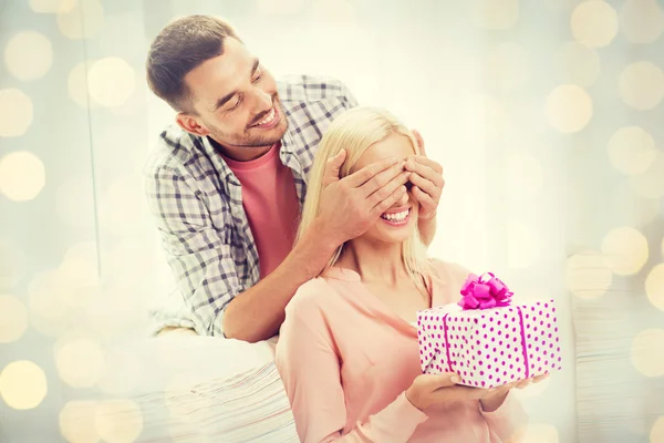 Happy man giving woman gift box at home — Stock Photo, Image