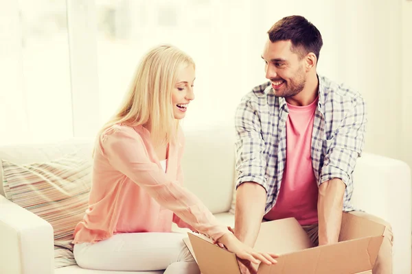 Casal feliz com caixa de pacote aberto em casa — Fotografia de Stock