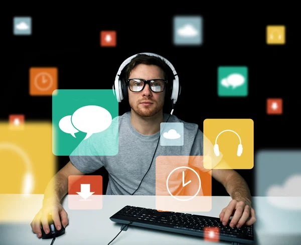 Hombre en auriculares con ordenador e iconos en pantalla —  Fotos de Stock