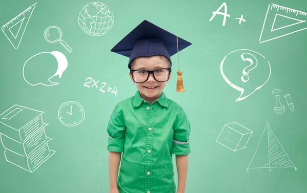 Boy v bakalářské klobouk a brýle nad tabule — Stock fotografie